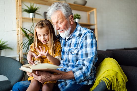 Grandfather reading book with granddaughter